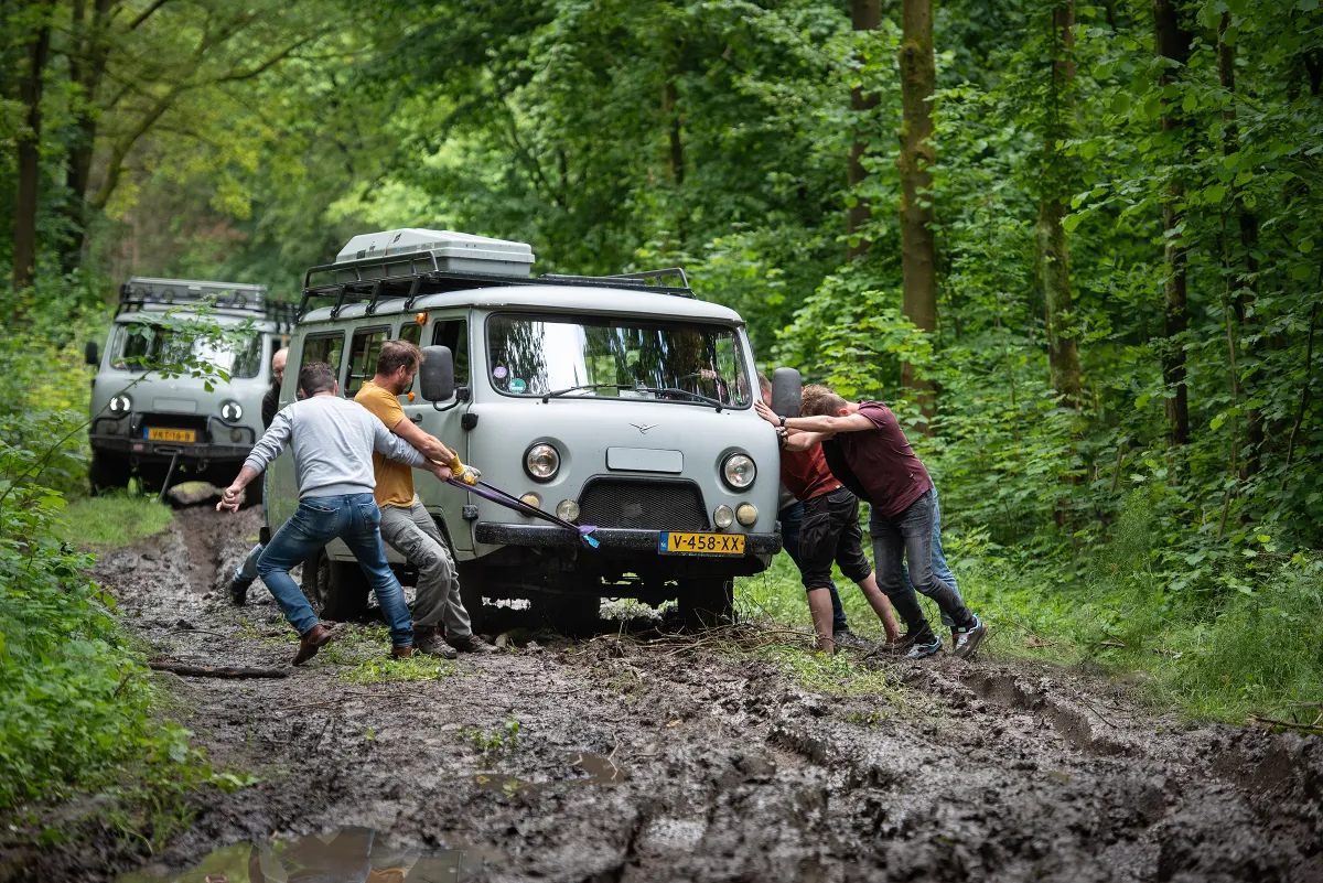 UAZ-liefhebbers helpen een Bukhanka op een modderig bospad